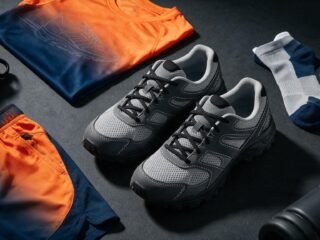 Athletic running shoes and sportswear apparel arranged in a flat lay on a dark charcoal surface